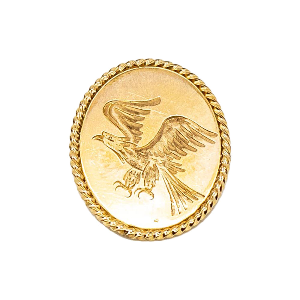Circular gold pin featuring an engraved image of a soaring eagle with wings outstretched.