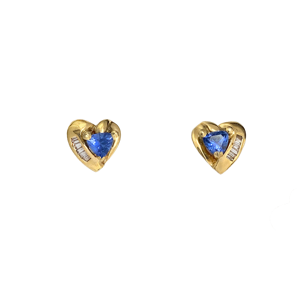 Pair of heart-shaped stud earrings featuring blue sapphires in the center, surrounded by baguette-cut diamonds.