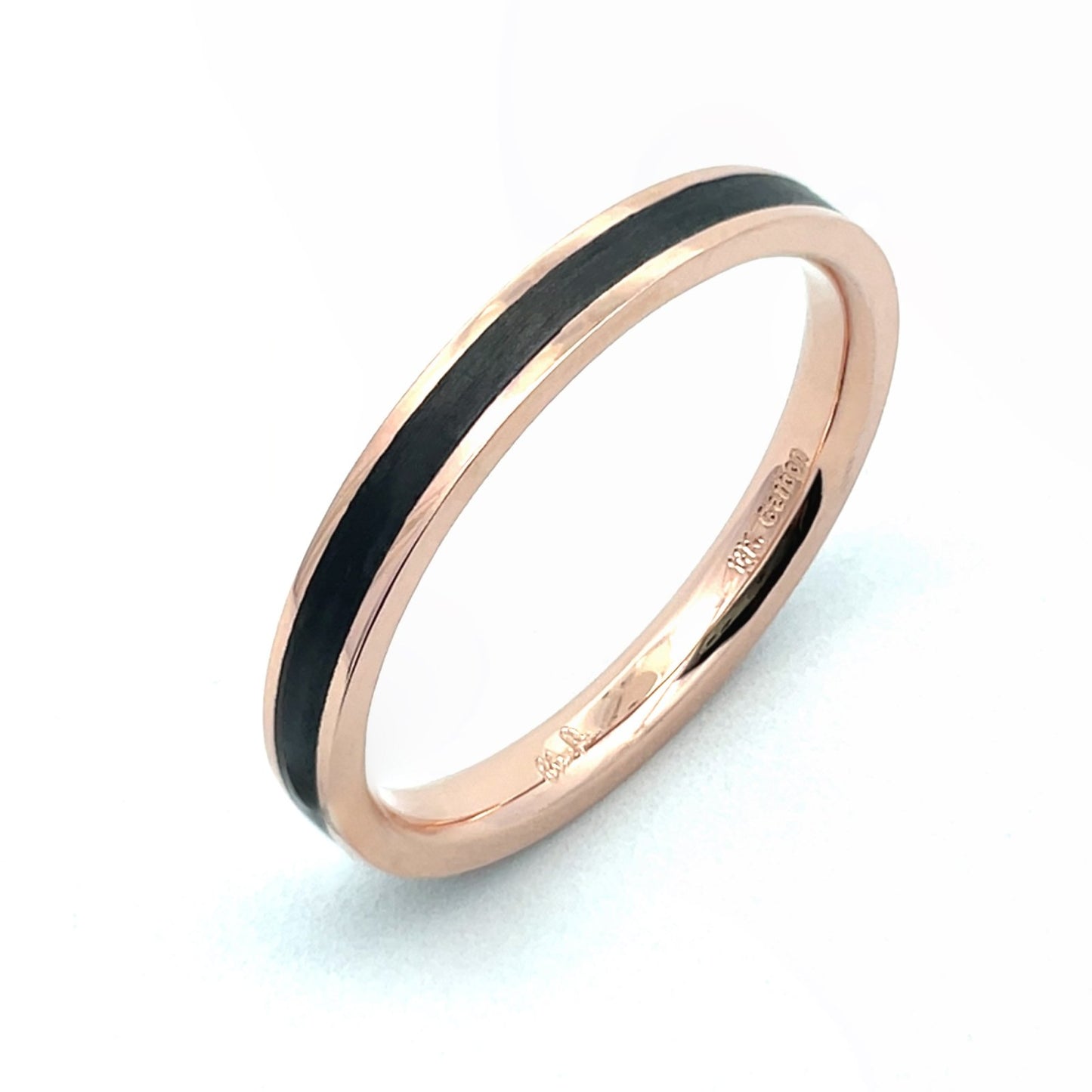 Rose gold ring with a black carbon fiber inlay on a white background.