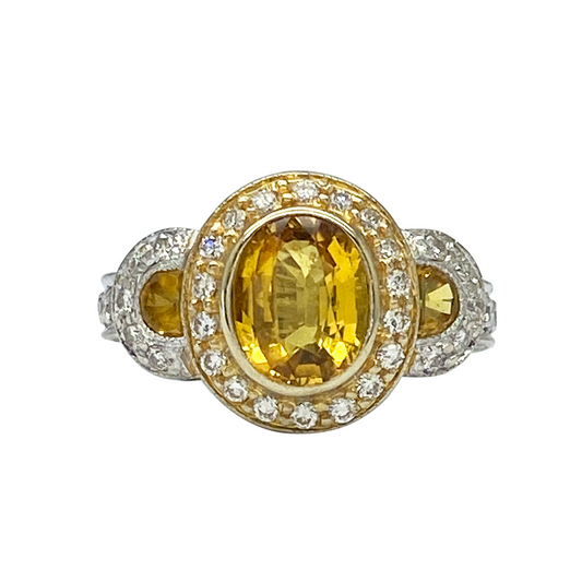 Gold and silver ring with a yellow gemstone on a white background