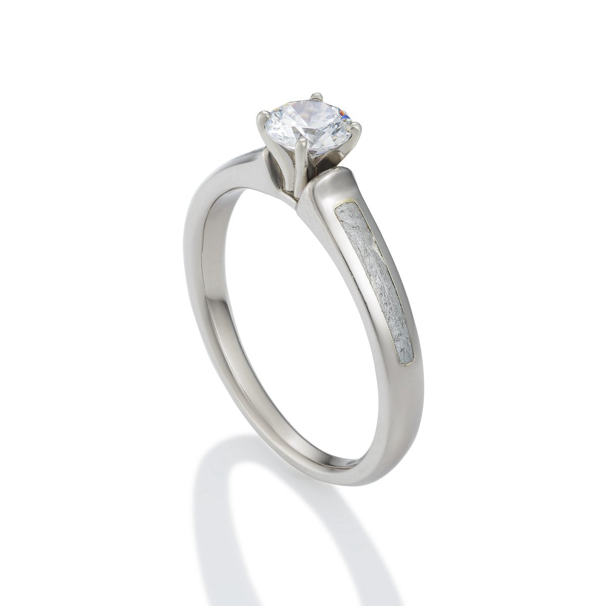 Silver engagement ring with a round diamond and a meteorite inlay on the band, on a white background.