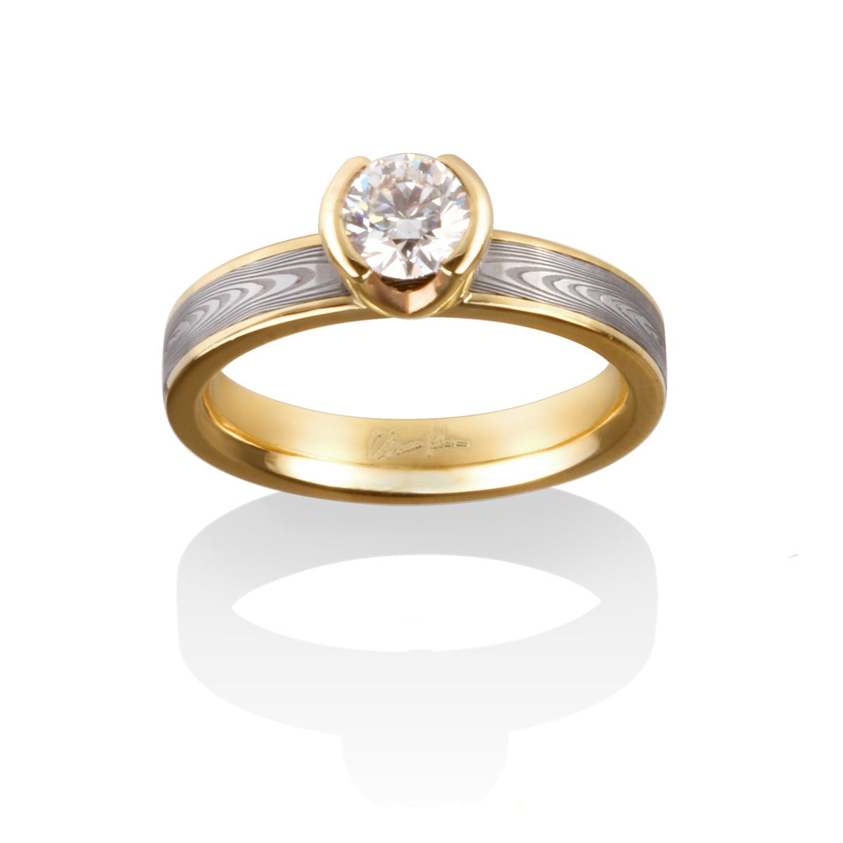 Yellow gold engagement ring with an oval diamond and a Damascus steel band on a white background