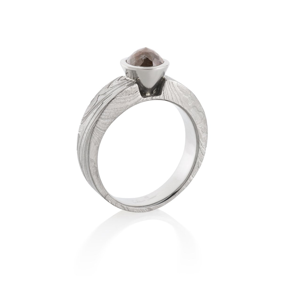 Silver ring with a brown diamond and a Damascus steel band on a white background