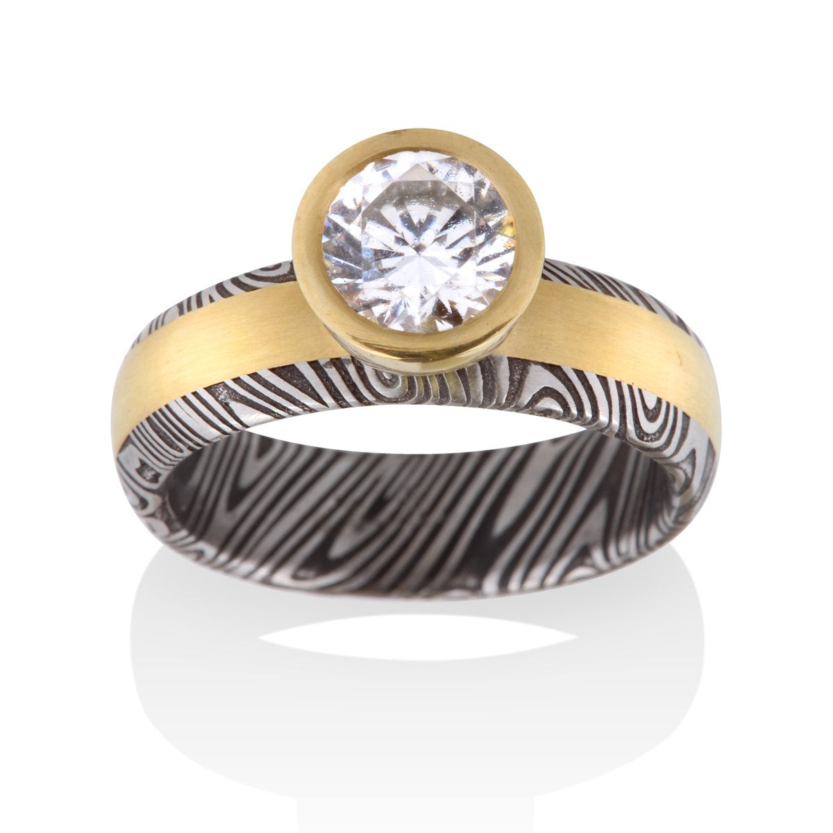 Yellow gold ring with a round diamond and a Damascus steel band on a white background