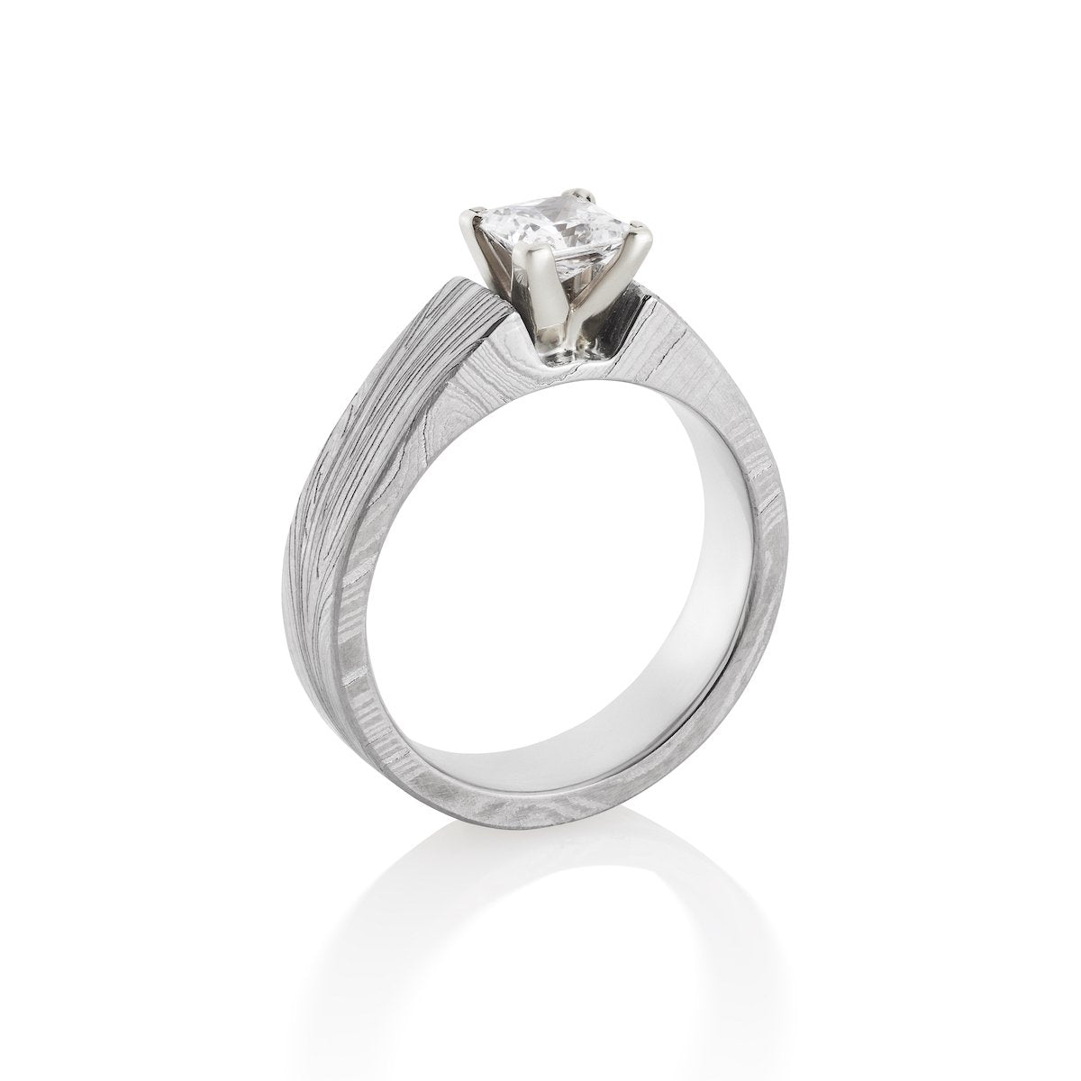 Silver ring with a princess-cut diamond and a Damascus steel band on a white background.