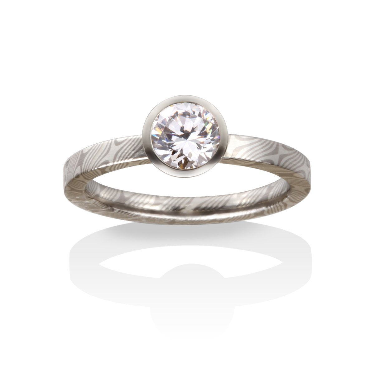 Silver ring with a round diamond and a Damascus steel band on a white background.