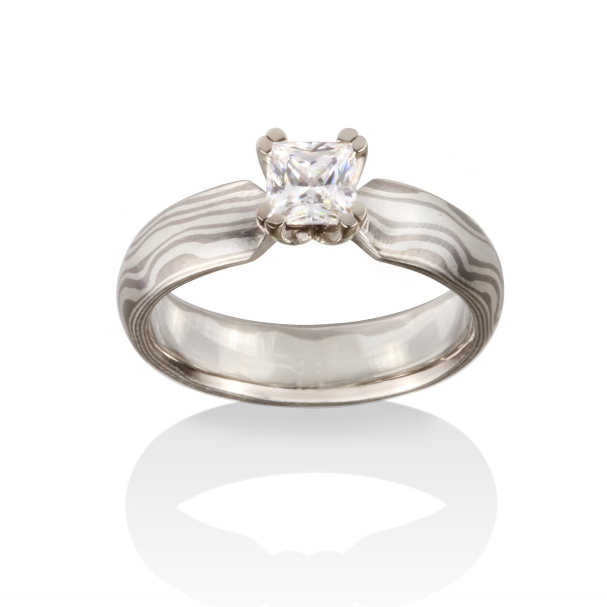 Silver ring with a princess-cut diamond and a Damascus steel band on a white background
