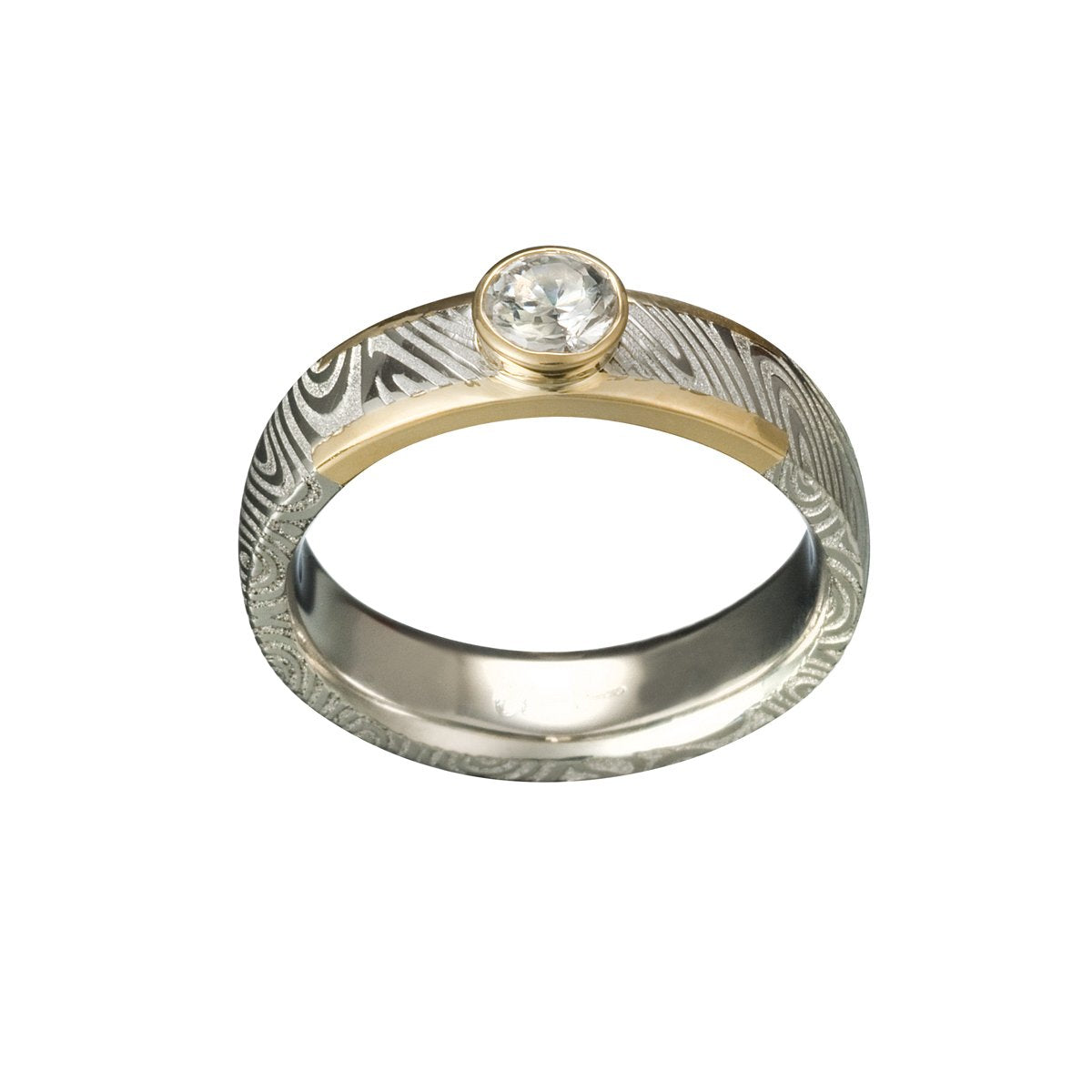 Two-tone gold ring with a round diamond and a Damascus steel band on a white background