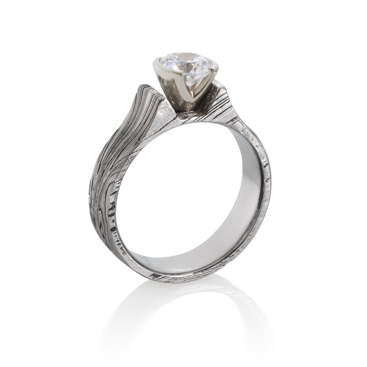 Silver ring with an oval diamond and a Damascus steel band on a white background