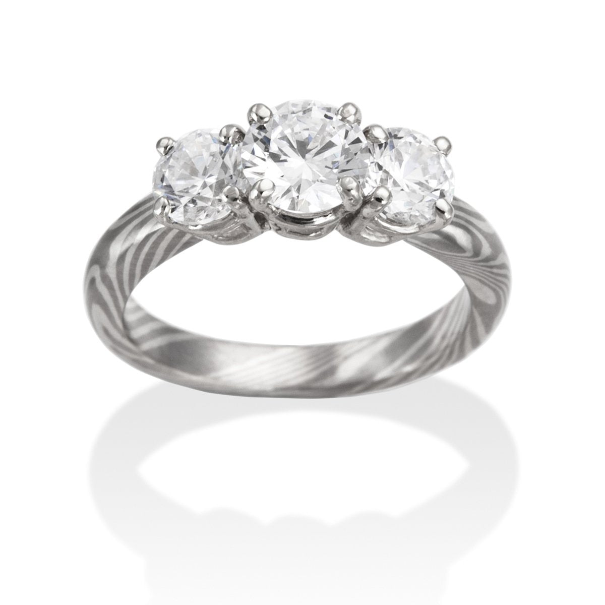 Silver ring with three round diamonds and a Damascus steel band on a white background