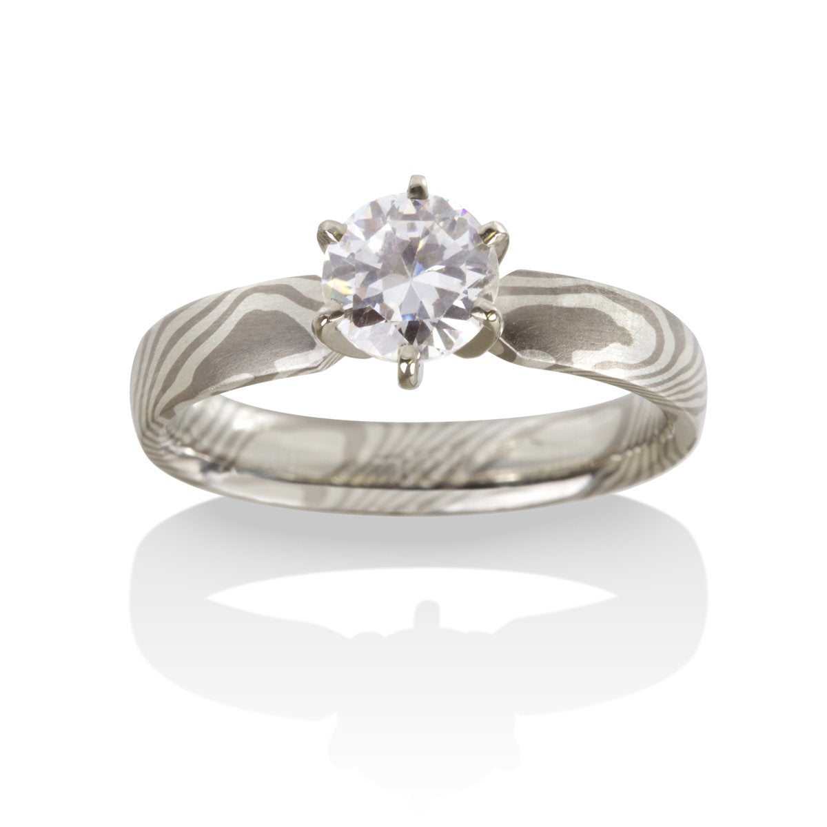 Silver ring with a round diamond and a Damascus steel band on a white background