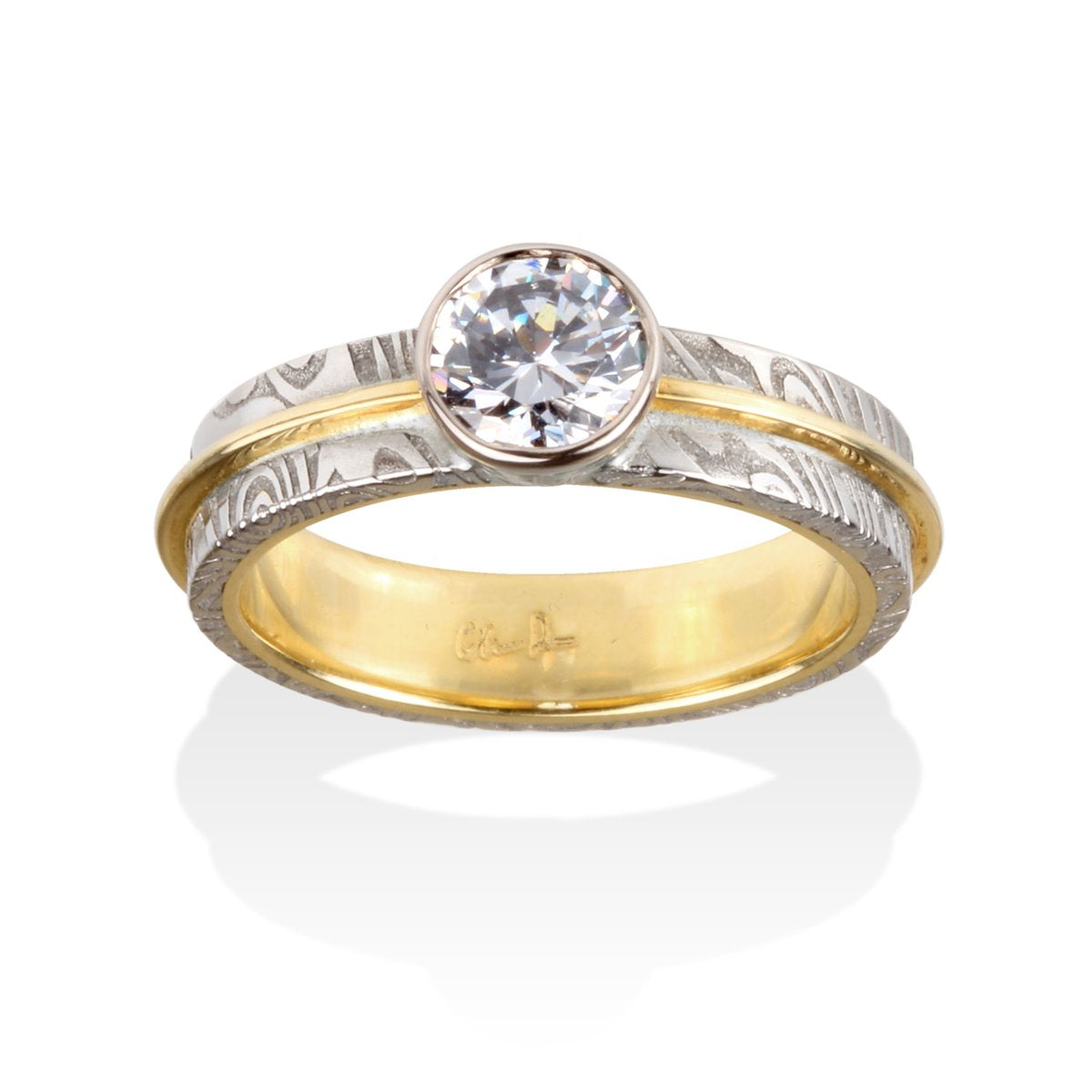 Two-tone gold ring with a round diamond and a Damascus steel band on a white background.