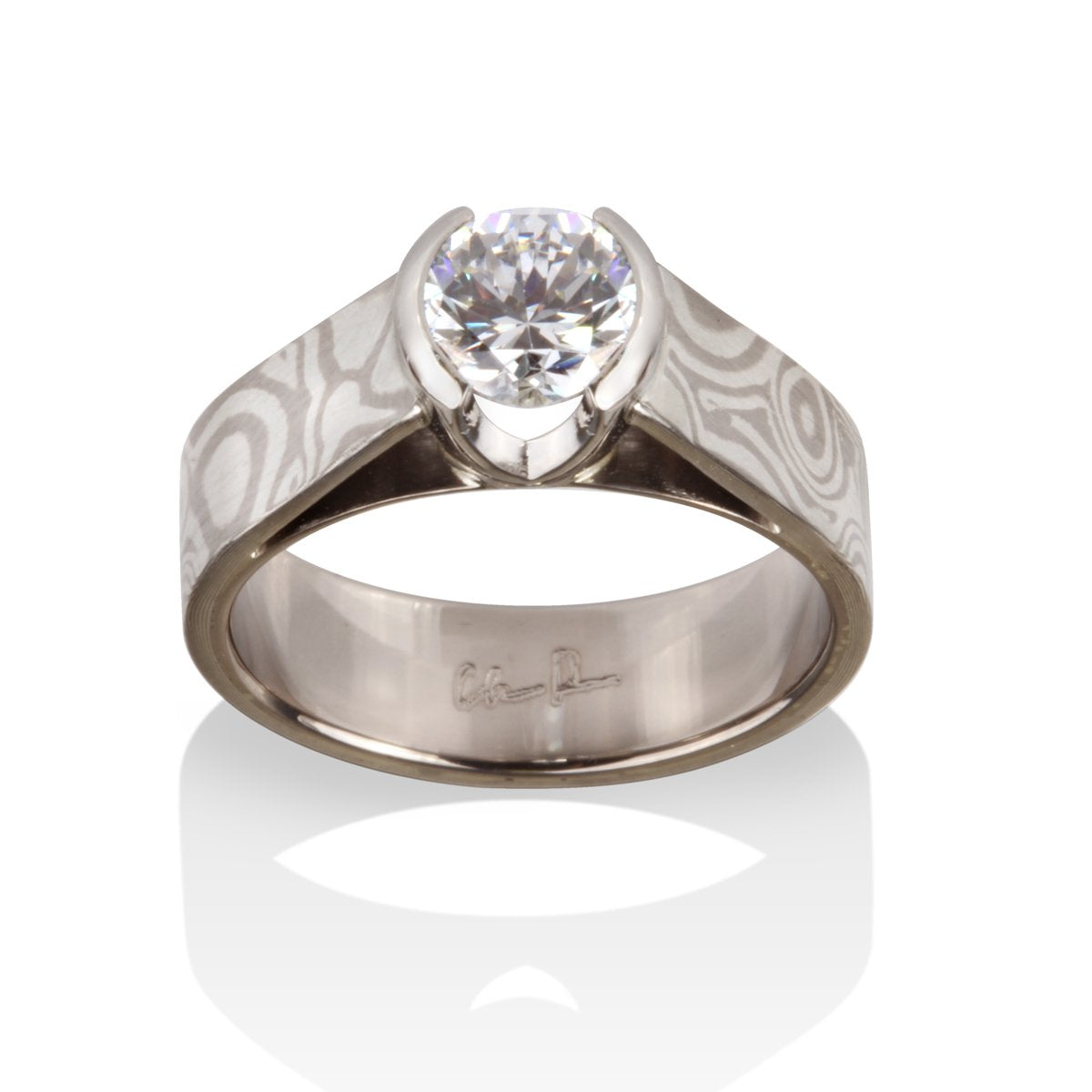 Titanium ring with a round diamond and a Damascus steel band on a white background.