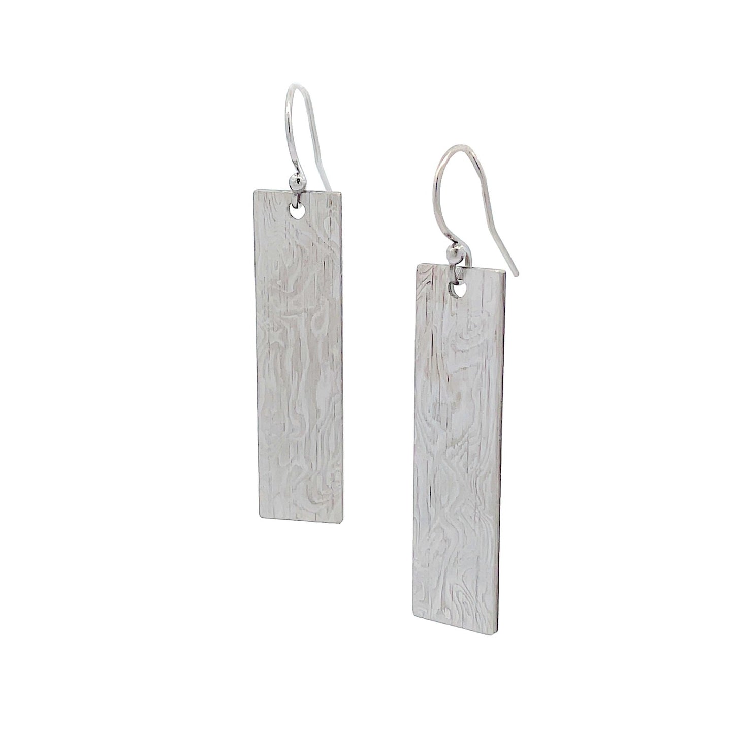 Pair of silver rectangular earrings with a textured Damascus steel on a white background.