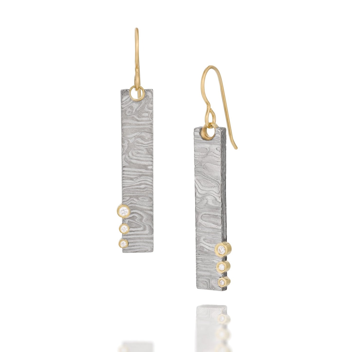 Pair of gold earrings with a damascus steel pattern, on a white background.