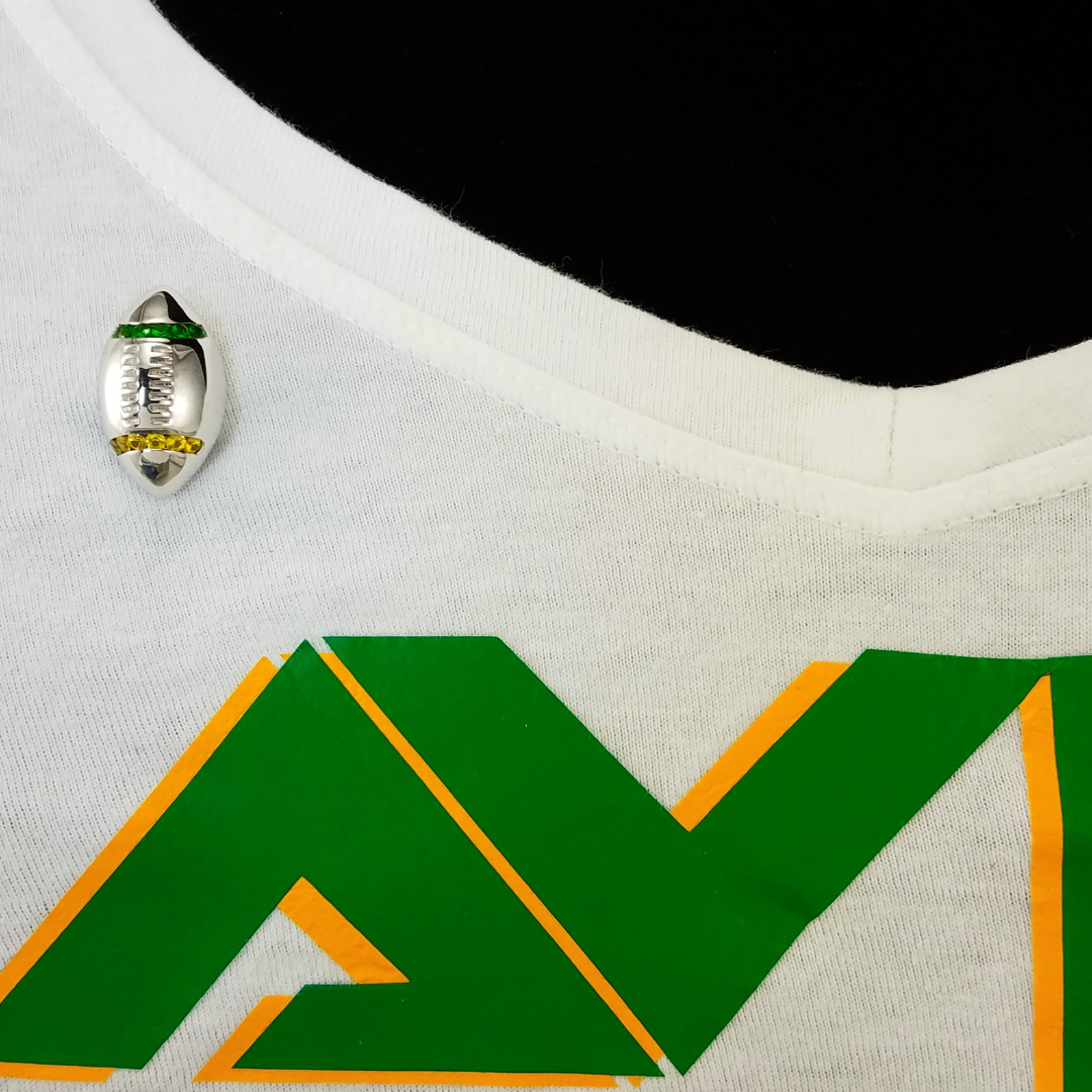 Close-up of a sports jersey with a logo and a pin on a white background