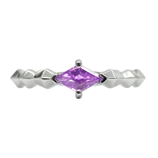 Silver ring with a purple kite-cut sapphire in the center. The ring has a textured band with a row of triangular shapes on each side.