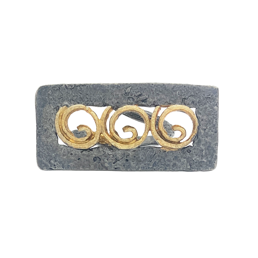 Rectangular ring with a textured, oxidized silver band featuring three raised, gold-toned spiral motifs within a rectangular cutout.