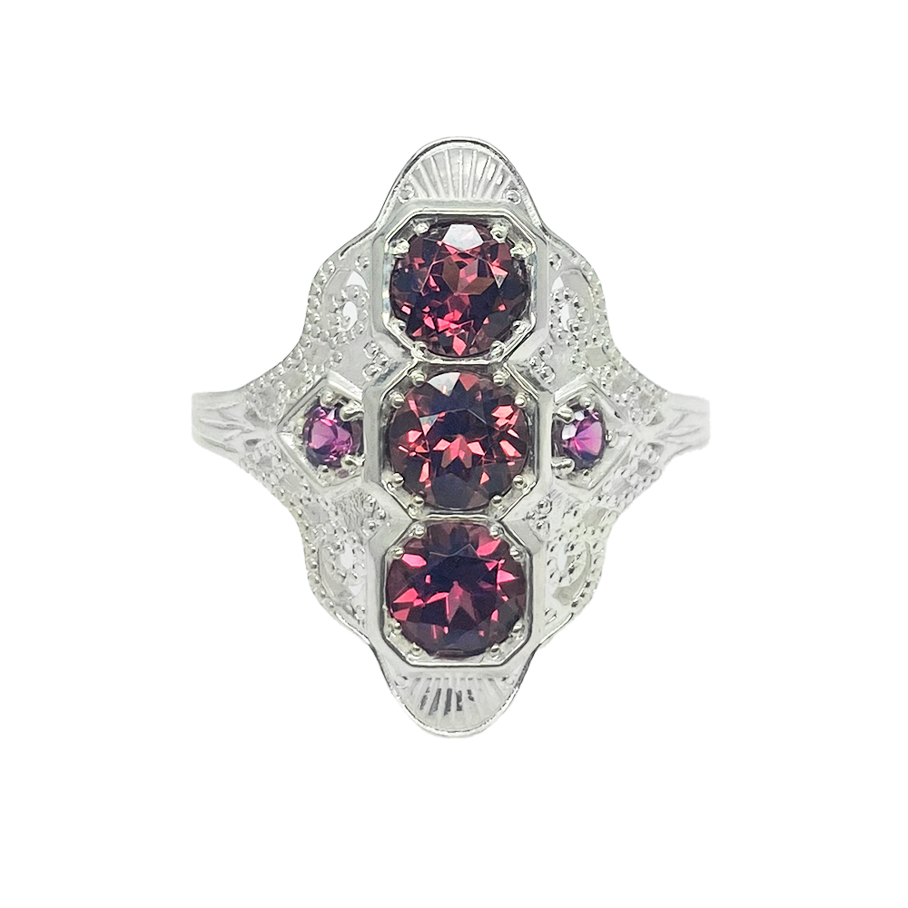 Silver ring with three almandine garnets surrounded by smaller diamonds in a geometric design.