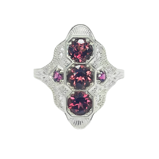 Silver ring with three almandine garnets surrounded by smaller diamonds in a geometric design.