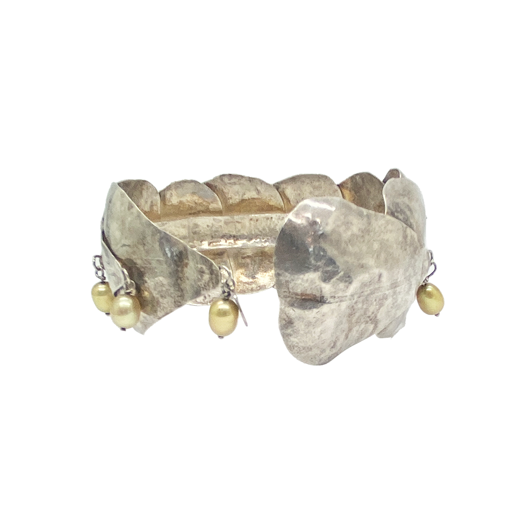 Silver band ring with a textured design resembling overlapping leaves. The bracelet features dangling pearls.