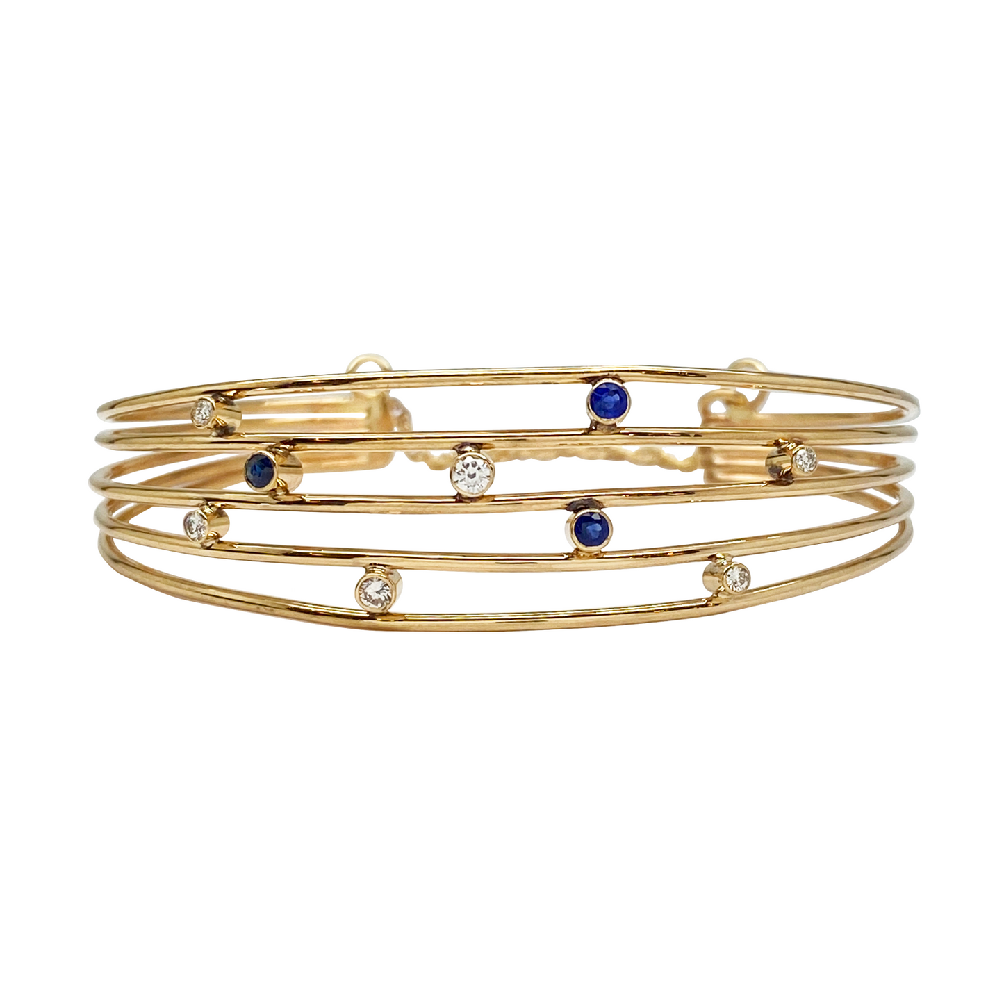 Gold multi-strand bangle with blue sapphire on a white background