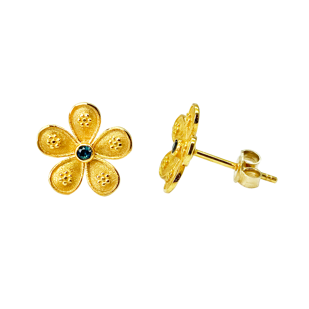 Gold flower-shaped stud earrings with blue sapphire centers, on a white background