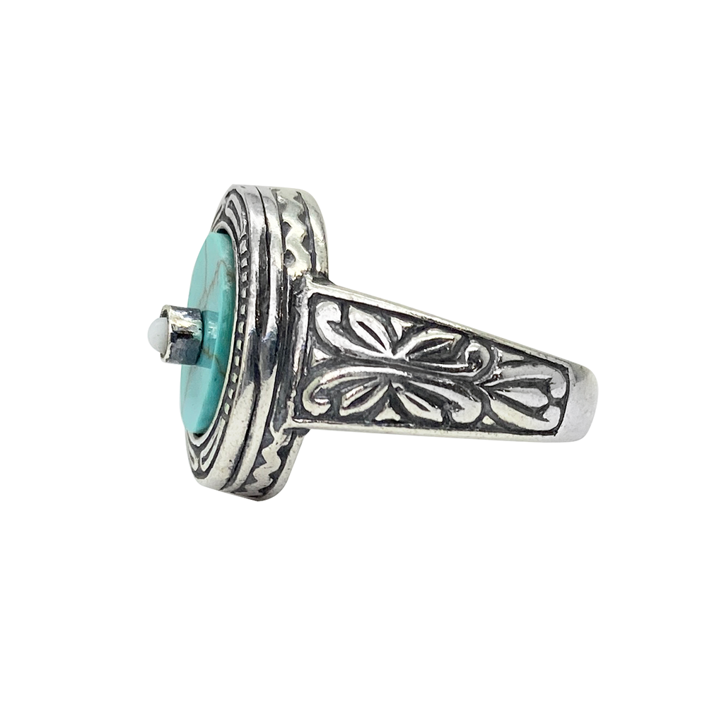 Silver ring with a turquoise center stone and intricate filigree detailing, on a white background