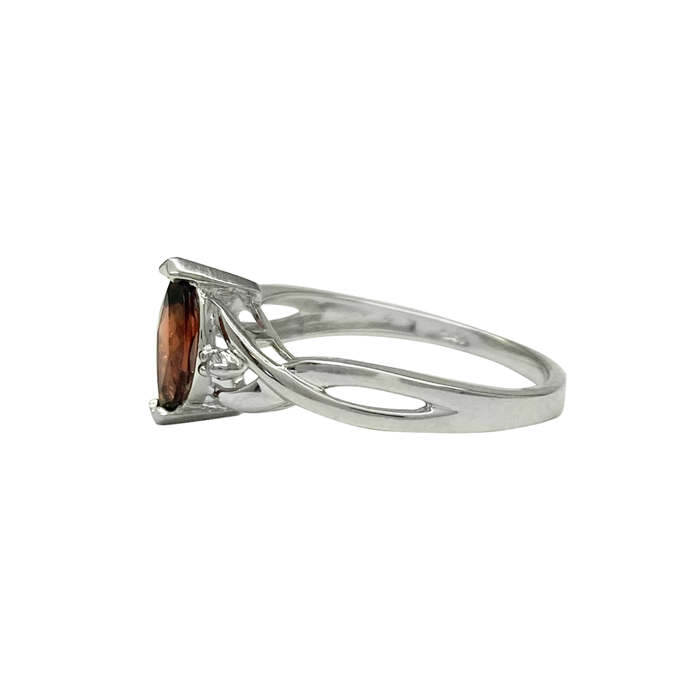 Silver ring with a round-cut garnet center stone and diamond accents, on a white background.
