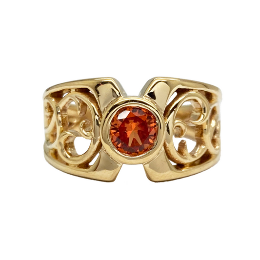 Gold ring with a round spessartite garnet set in an Art Nouveau-inspired filigree design.
