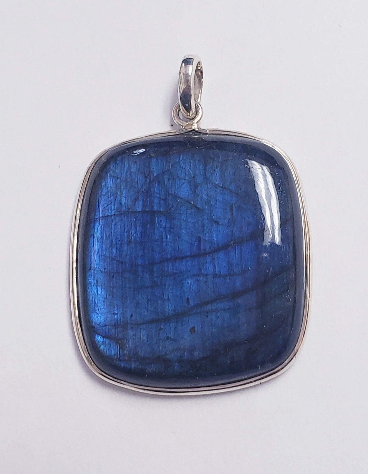 Slver pendant with a large, square-cut blue labradorite gemstone on a white background.
