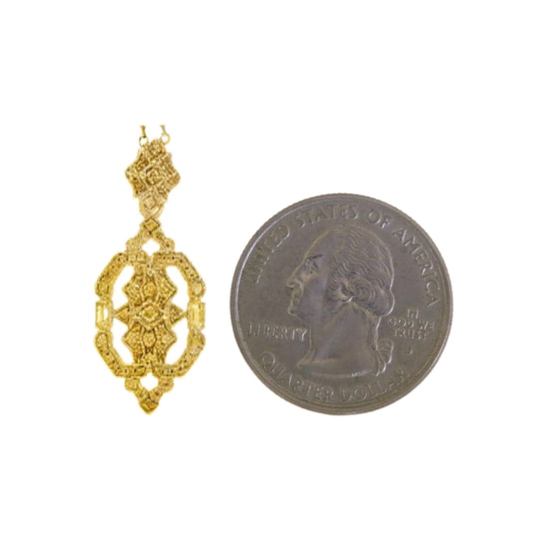 Gold pendant next to a U.S. quarter coin on a white background
