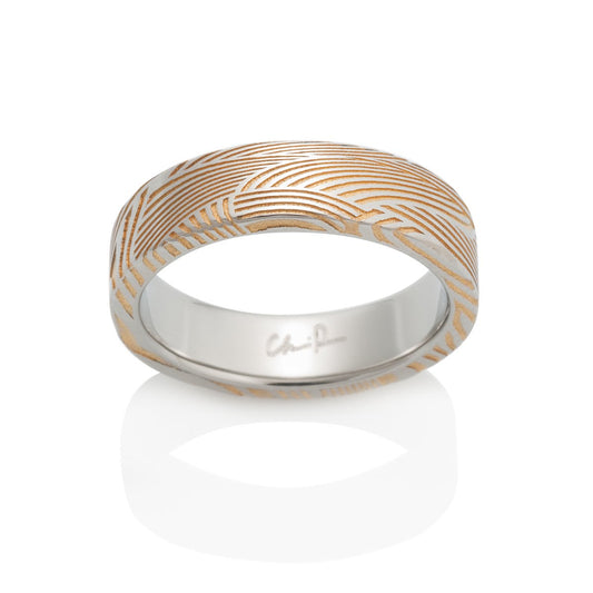 Two-tone gold ring with a textured pattern on a white background.