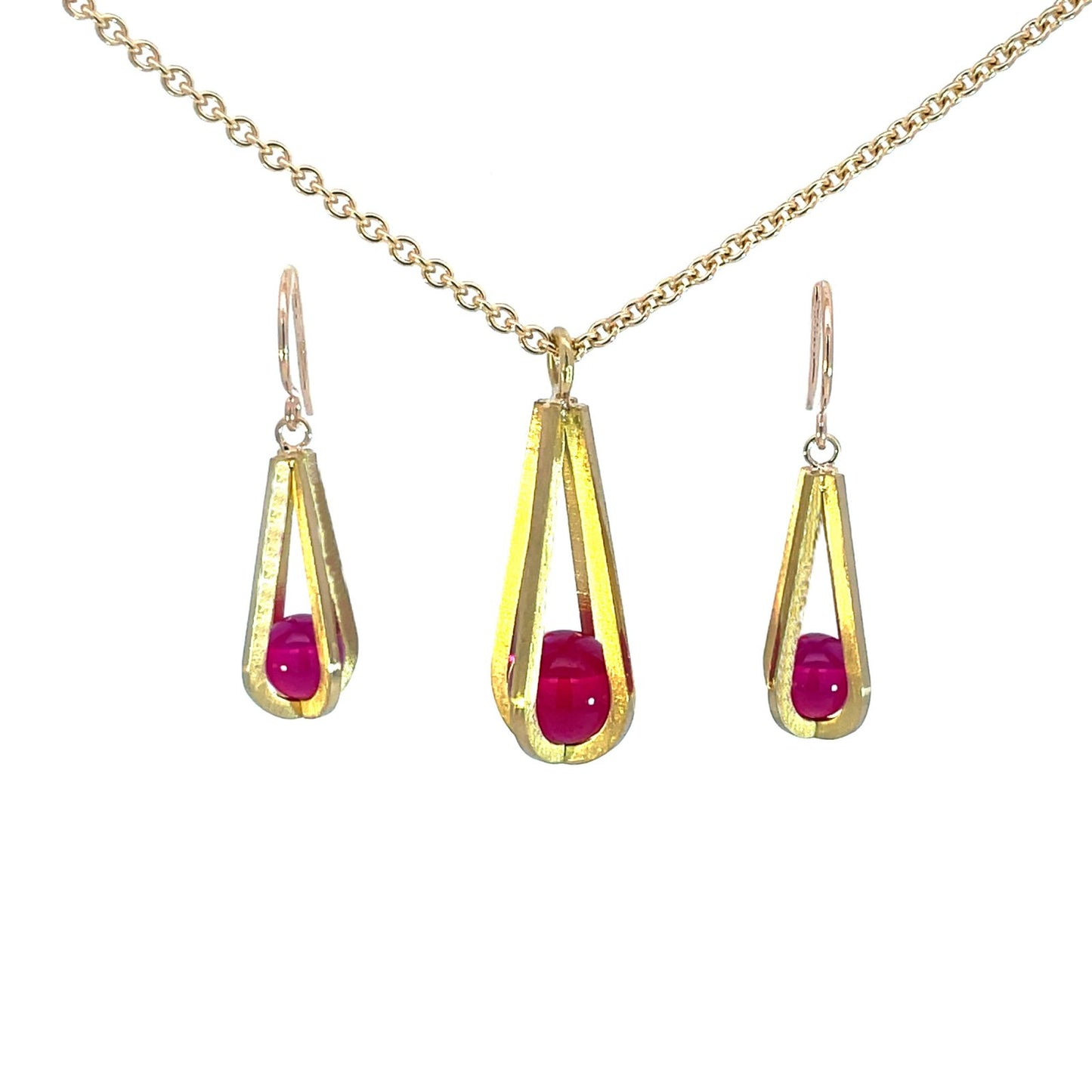 Gold pendant shaped like a teardrop, with a red gemstone suspended inside, on a white background
