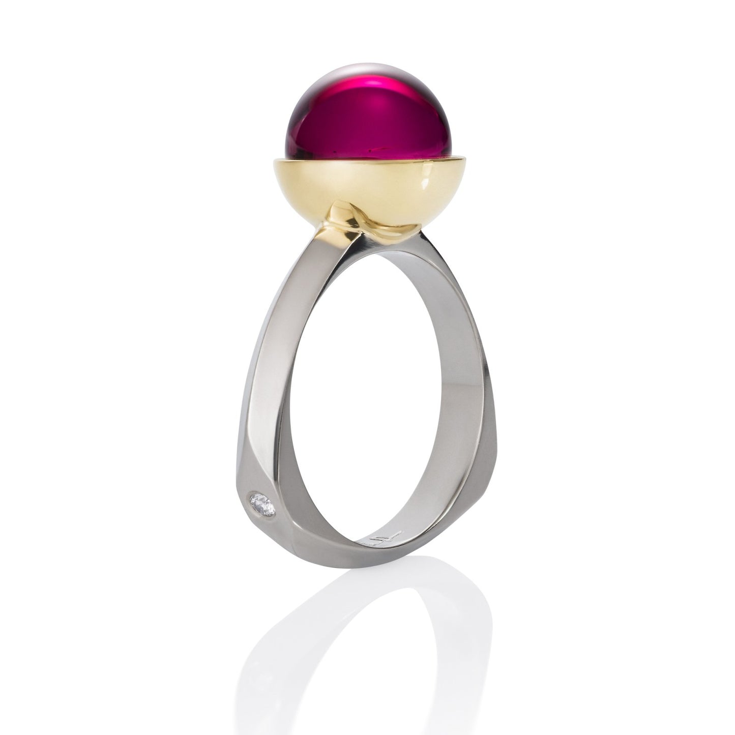Ring with a large, round, red gemstone set in a gold bezel, on a white background.