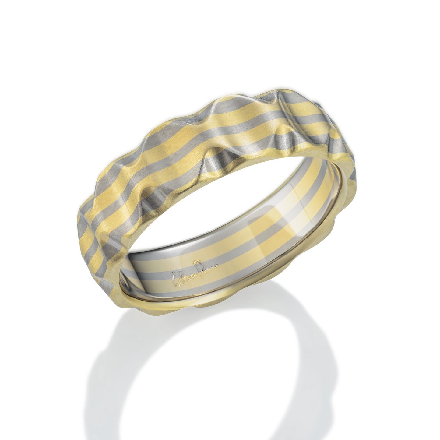 Gold and titanium band ring with a textured, striped pattern on a white background