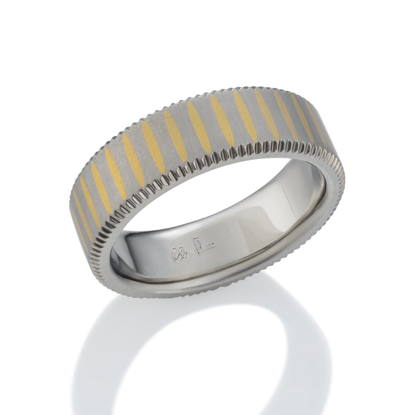 Gold and titanium band ring with a striped pattern on a white background