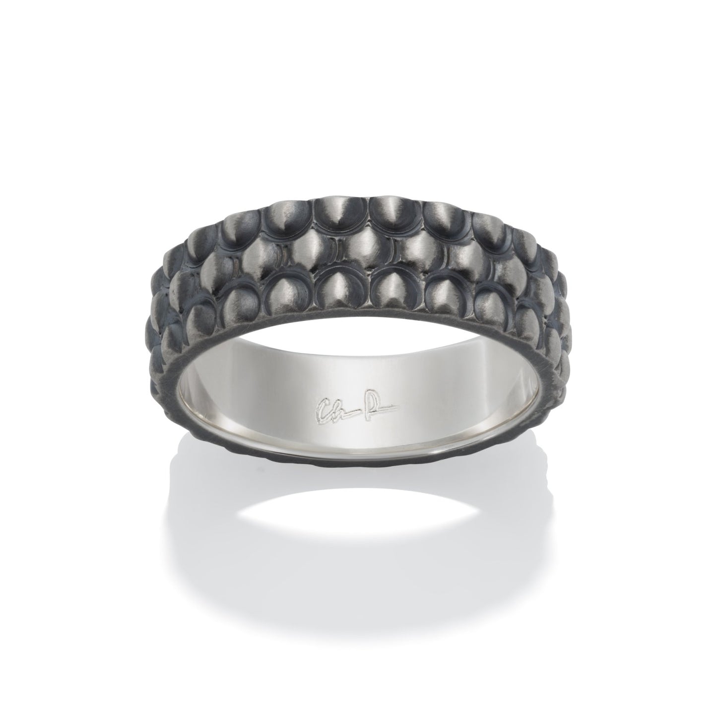 Silver ring with a textured, dome-shaped pattern resembling scales, on a white background