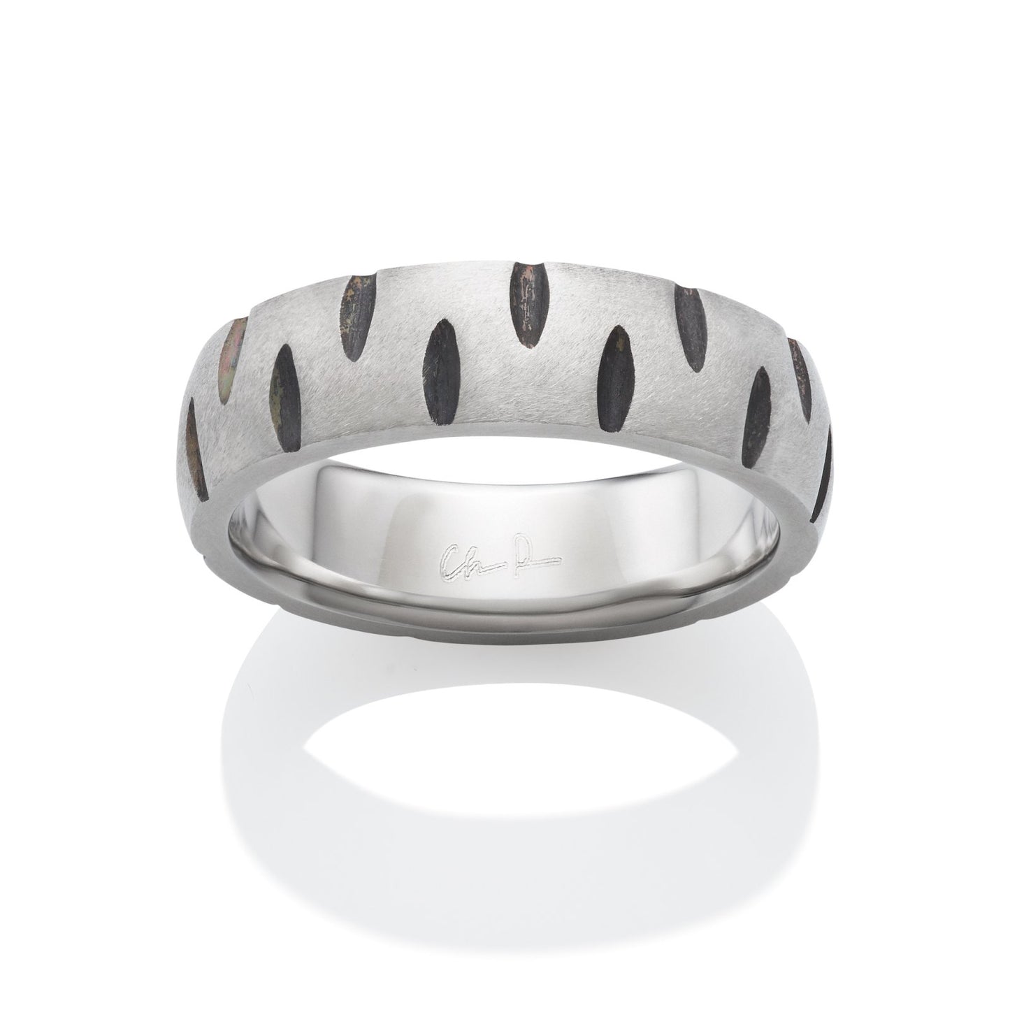 Silver ring with a textured, oval-shaped pattern, with black accents, on a white background.