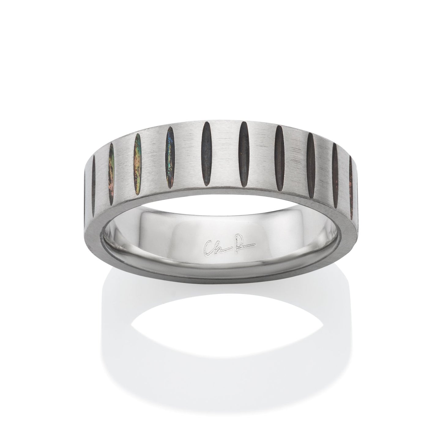 Silver ring with a textured, oval-shaped pattern, with black accents, on a white background