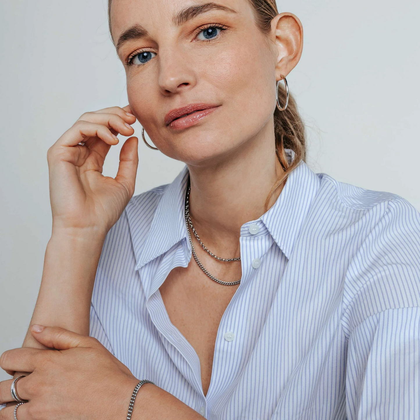 Woman wearing a light blue striped shirt with a neutral background