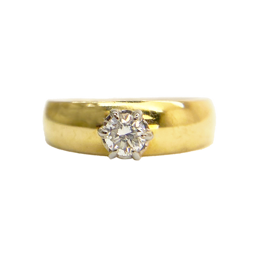Yellow gold ring with a round-cut diamond center stone on a white background.