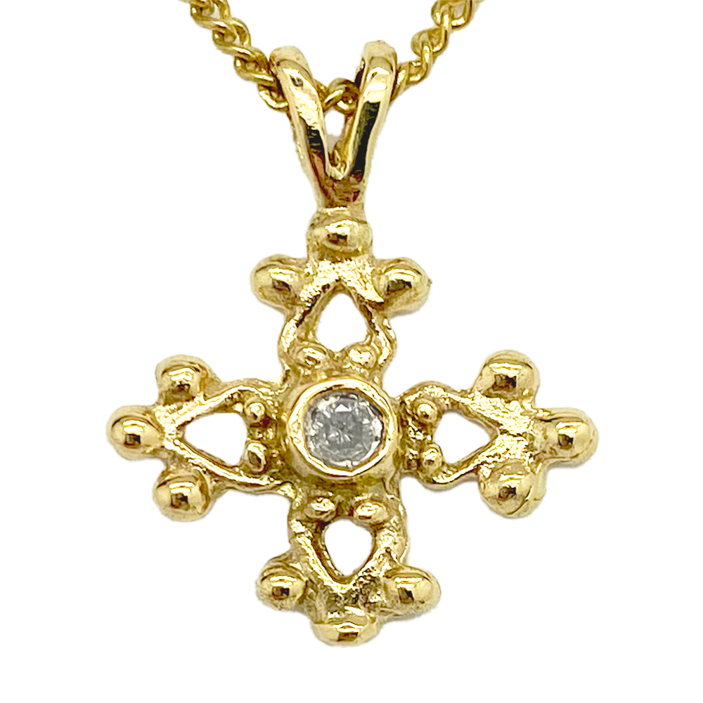 Gold cross pendant with a center diamond, on a white background