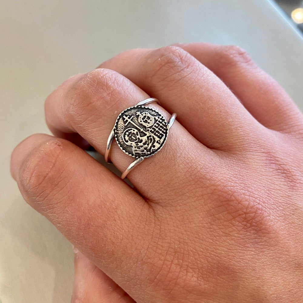 Silver ring featuring a circular medallion with an embossed image of a saint holding a cross and a staff, surrounded by a double-wire band.