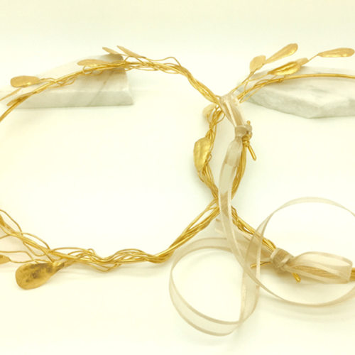 Pair of gold Stefana crowns, traditional Greek wedding crowns, connected by a white ribbon. 