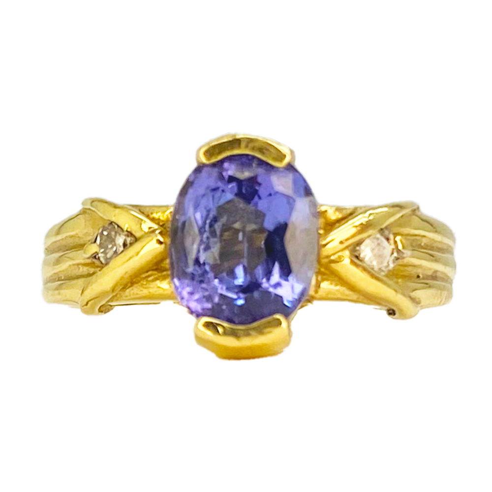 Gold ring with an oval-shaped tanzanite center stone and two smaller diamond accents.