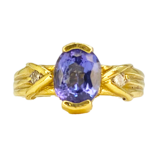 Gold ring with an oval-shaped tanzanite center stone and two smaller diamond accents.