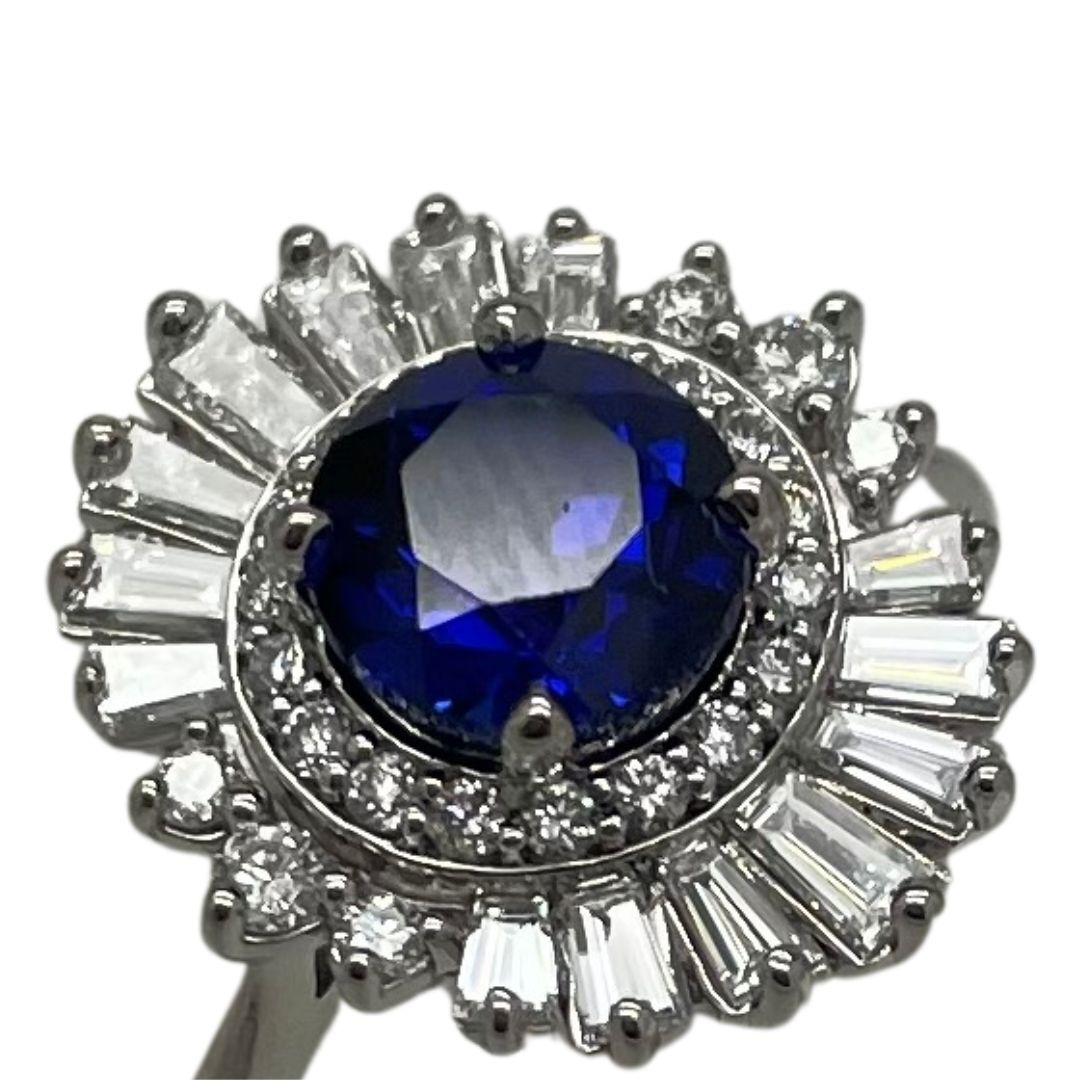 Silver ring with a blue gemstone and clear stones on a white background