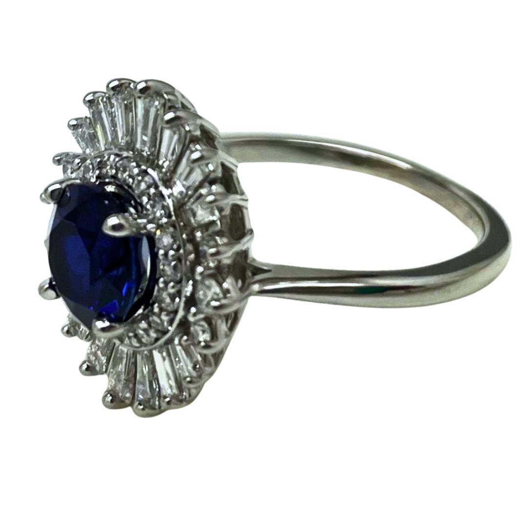 Silver ring with a blue gemstone and diamond accents on a white background