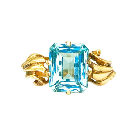 Gold ring with a blue topaz stone set in an Art Deco-style setting
